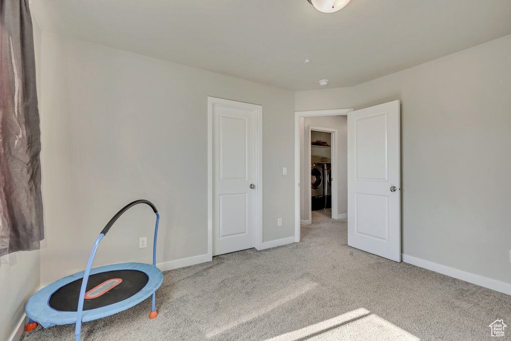 Unfurnished bedroom with washing machine and dryer, carpet flooring, and baseboards