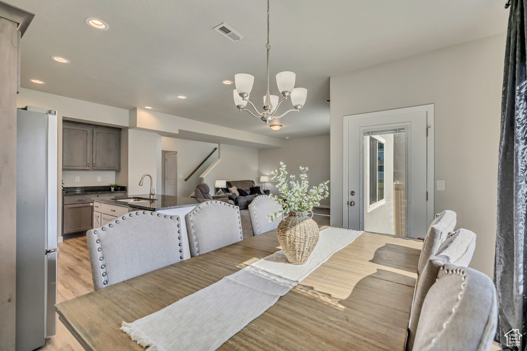 Dining area featuring light wood finished floors, recessed lighting, a chandelier, and stairs