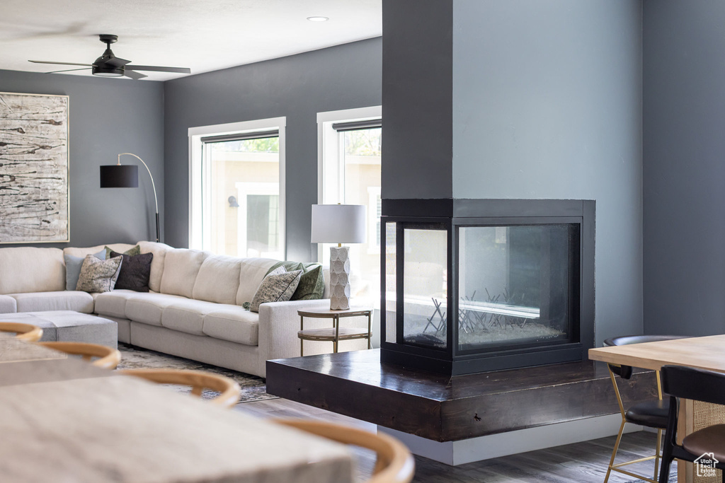 Living area with wood finished floors, ceiling fan, and a multi sided fireplace