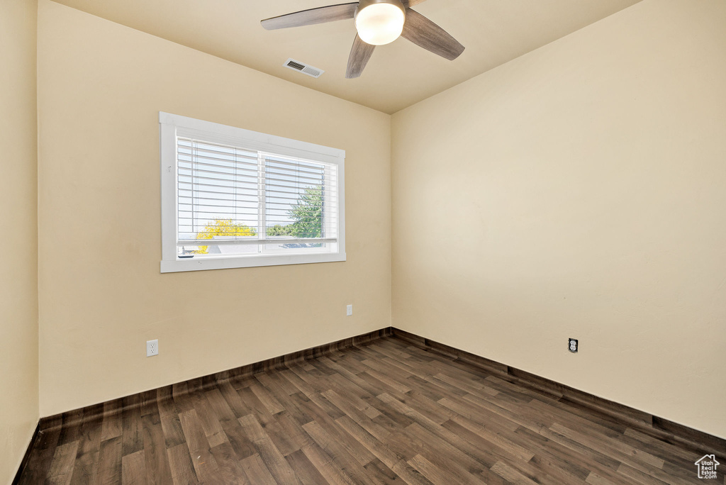 Unfurnished room with dark wood-style floors, a ceiling fan, and baseboards