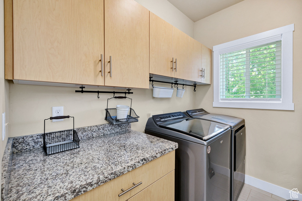 Washroom featuring washing machine and clothes dryer, cabinet space, and baseboards