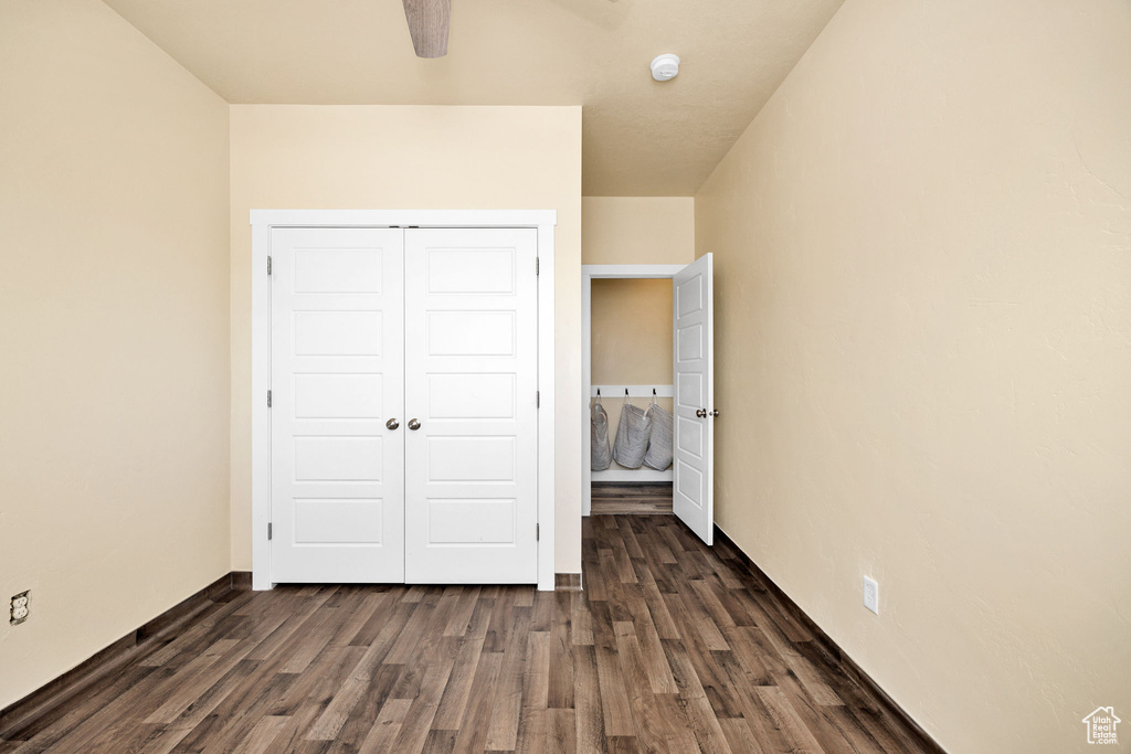 Unfurnished bedroom featuring dark wood finished floors, a closet, and ceiling fan
