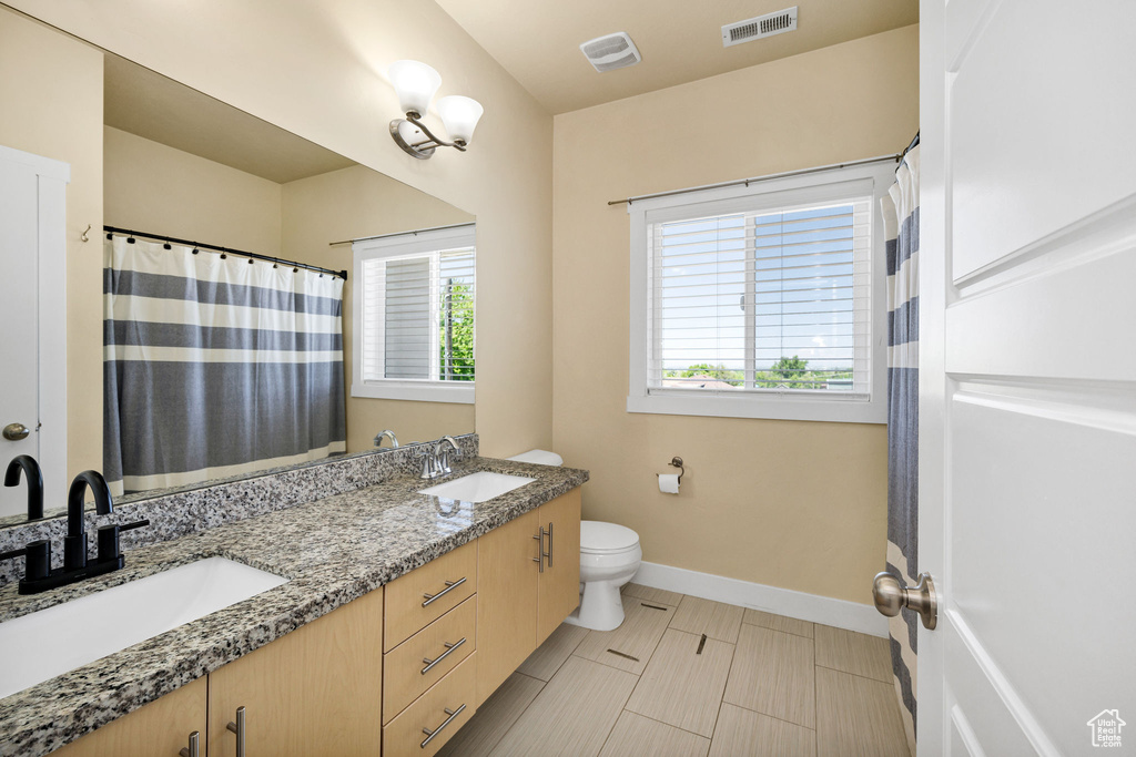 Bathroom featuring double vanity, toilet, baseboards, and curtained shower