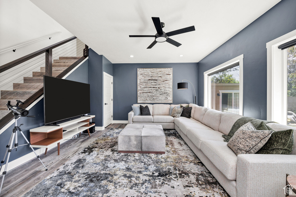 Living room featuring wood finished floors, ceiling fan, stairway, baseboards, and recessed lighting