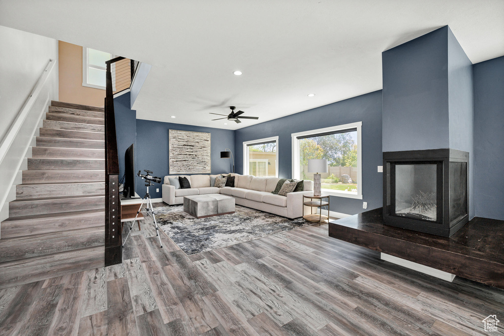 Living area featuring stairs, wood finished floors, ceiling fan, a multi sided fireplace, and recessed lighting