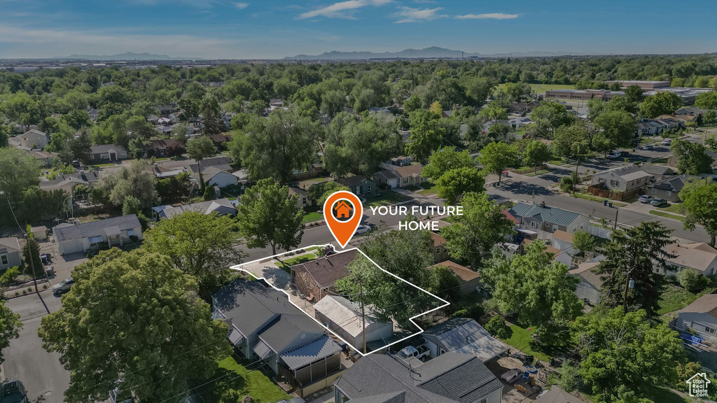 Aerial view of property and surrounding area featuring nearby suburban area and a mountain backdrop