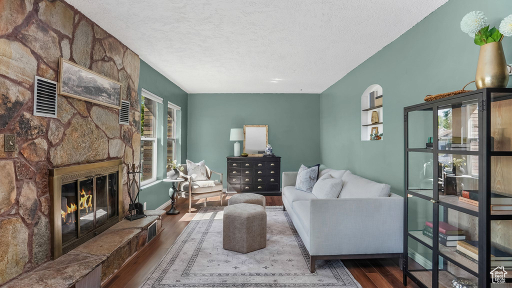Living room with wood finished floors, a textured ceiling, a fireplace, and baseboards