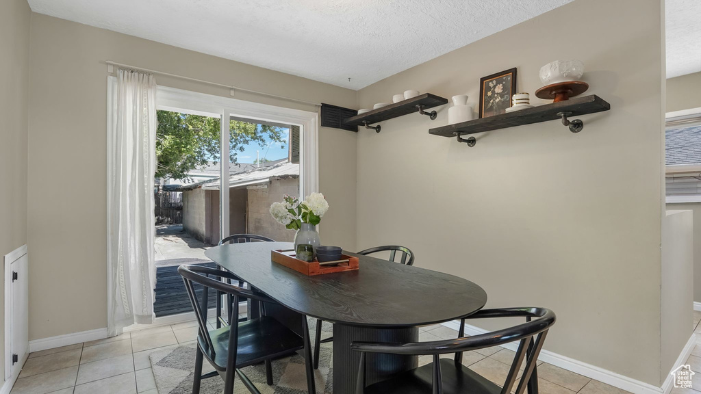 Dining area with light tile patterned floors, baseboards, and a textured ceiling