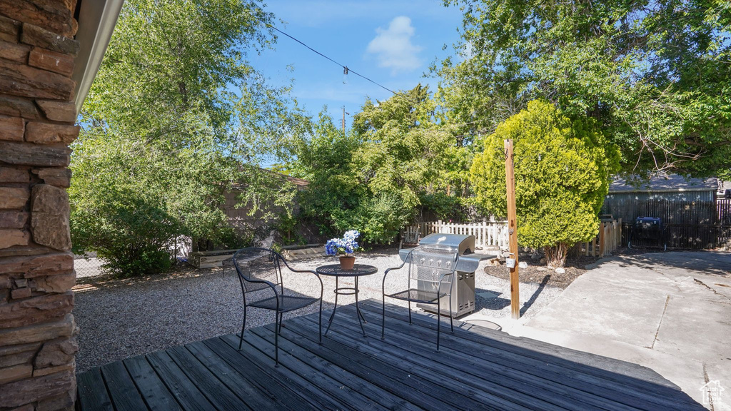 Wooden deck featuring a grill, a fenced backyard, and a patio area