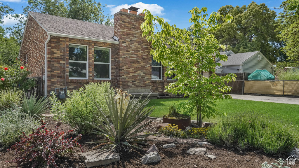 View of side of property with a chimney, brick siding, and a shingled roof