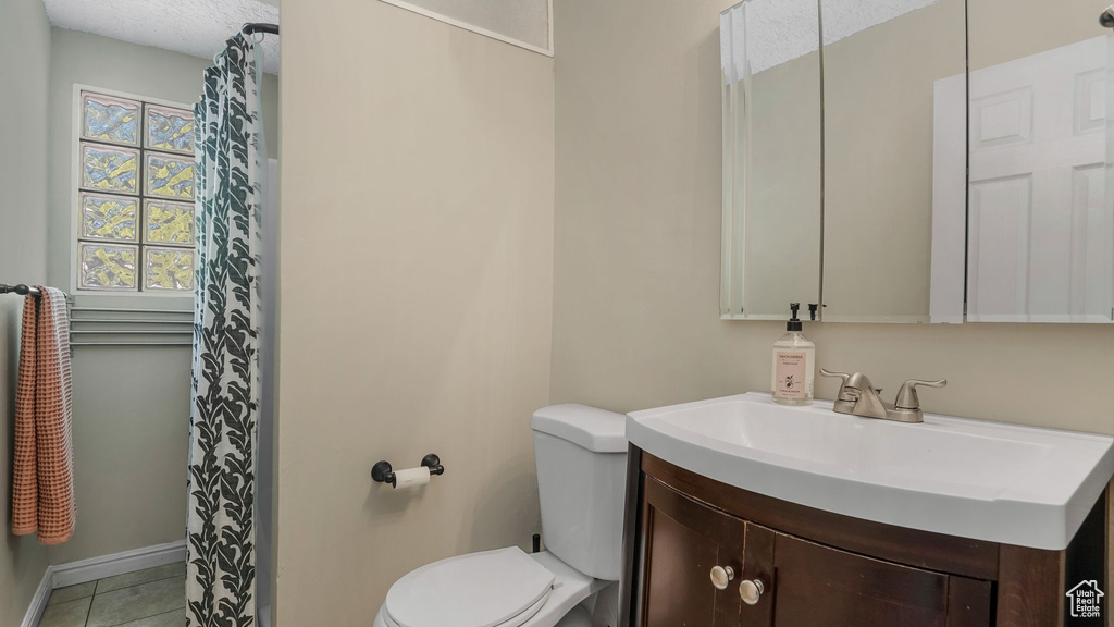 Full bath with toilet, vanity, tile patterned floors, a shower with shower curtain, and baseboards