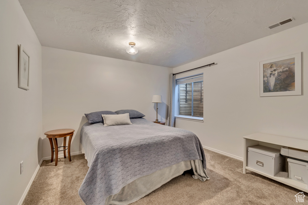 Bedroom with carpet flooring, baseboards, and a textured ceiling