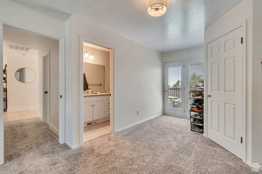 Bedroom featuring light colored carpet, access to exterior, ensuite bathroom, and baseboards