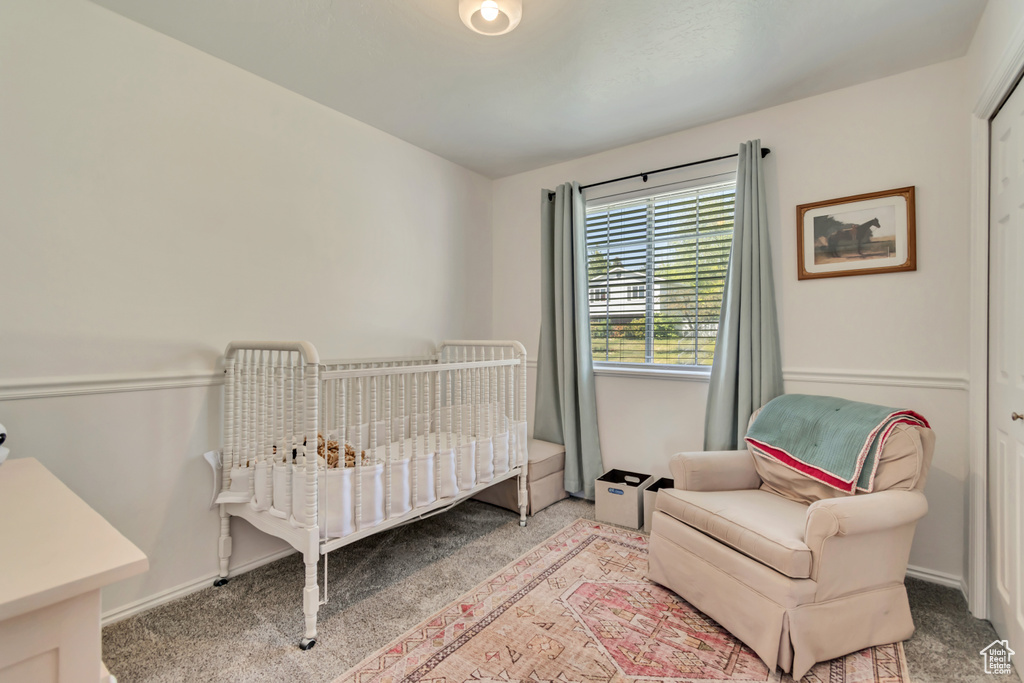 Carpeted bedroom featuring a crib and baseboards