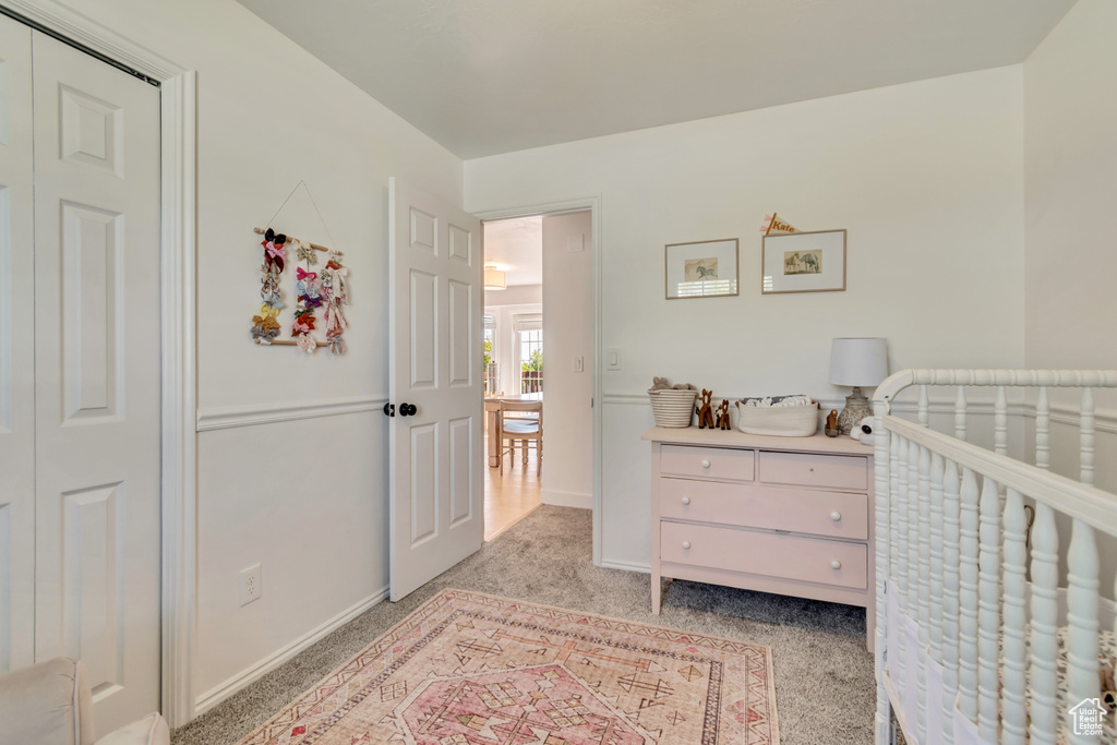 Bedroom featuring light carpet, a nursery area, and baseboards