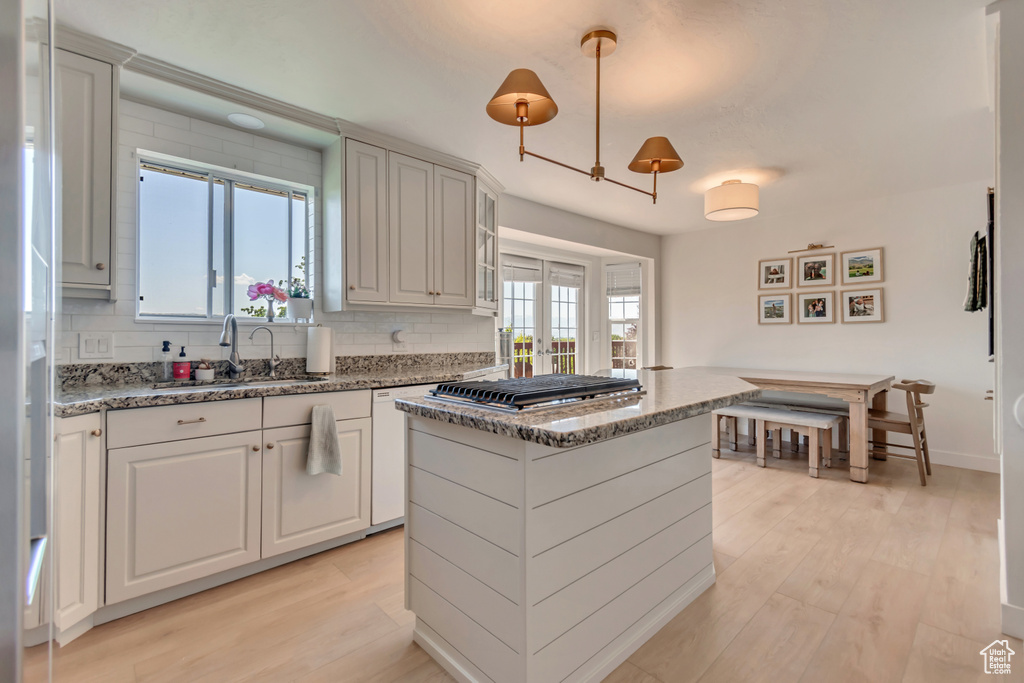 Kitchen featuring a sink, backsplash, light wood-style floors, and stainless steel gas stovetop