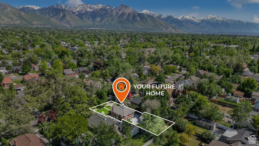Aerial view of residential area with property boundaries highlighted and a mountain backdrop