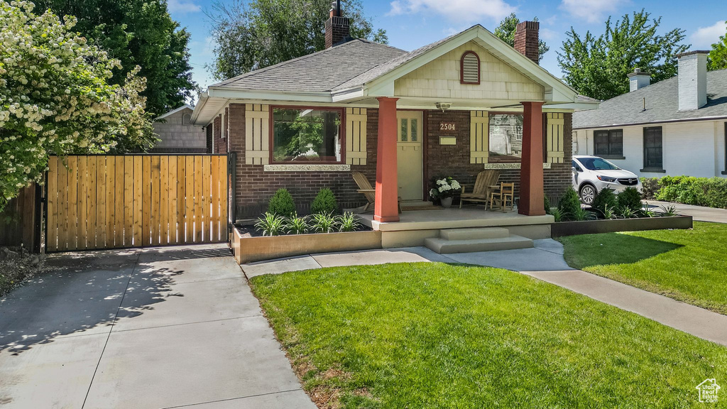Bungalow-style house featuring covered porch, brick siding, and a chimney