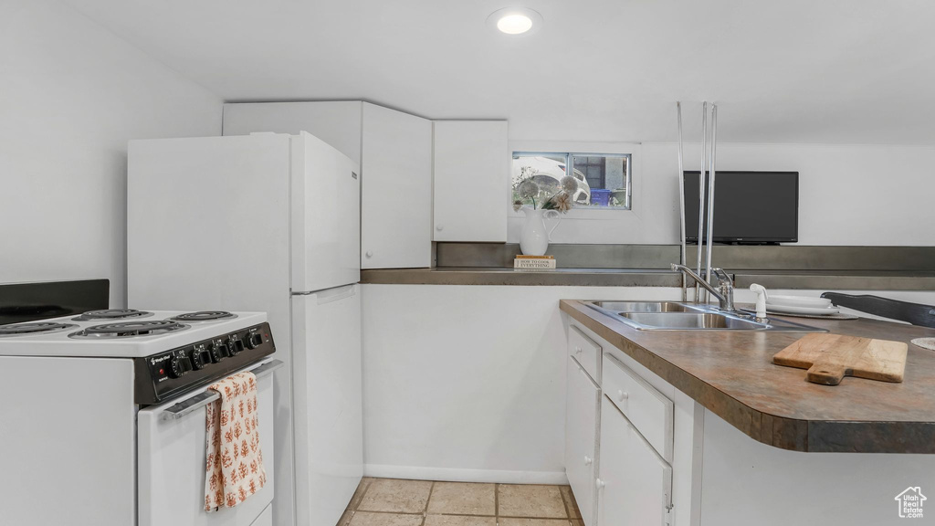 Kitchen featuring white appliances, a sink, white cabinets, and baseboards