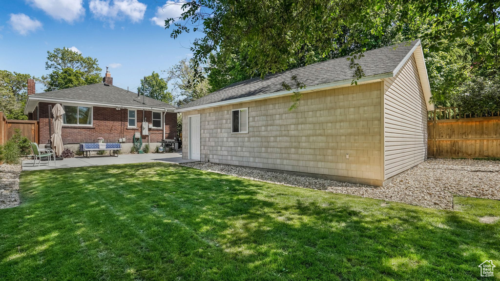 Rear view of house with an outbuilding, a patio area, and brick siding