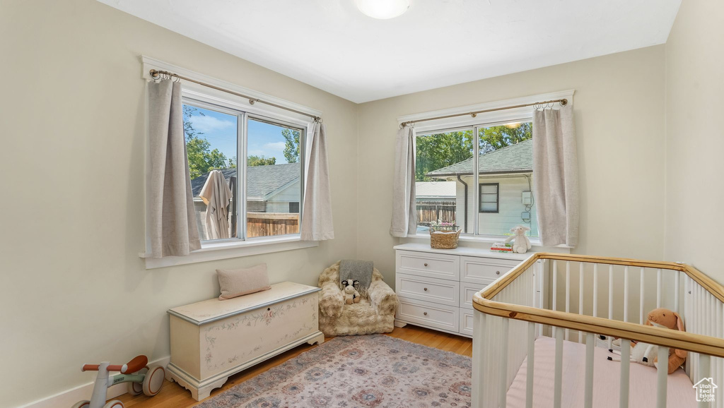 Bedroom with light wood-style floors and a nursery area
