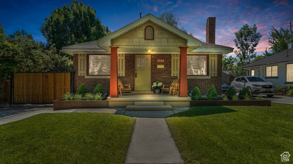 Bungalow-style home featuring brick siding, a porch, and a chimney