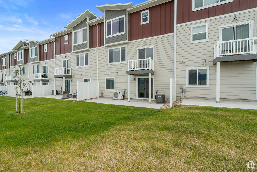 Rear view of property featuring board and batten siding, cooling unit, a cooling unit, and a yard