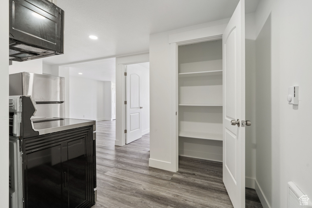 Kitchen with wood finished floors, baseboards, recessed lighting, and black microwave
