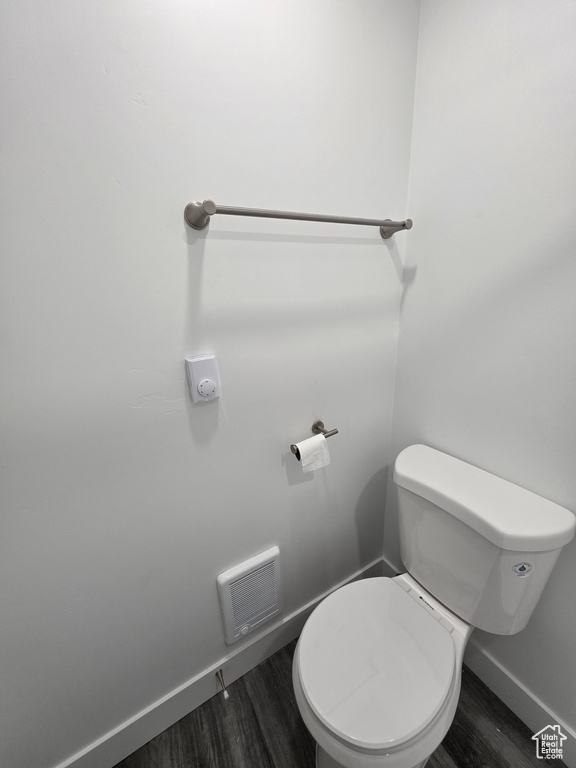 Bathroom featuring baseboards, wood finished floors, and toilet