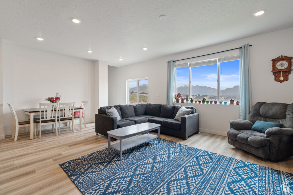 Living room with light wood finished floors, recessed lighting, a mountain view, and baseboards