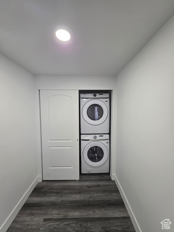 Laundry room featuring stacked washer / drying machine, baseboards, and dark wood-type flooring