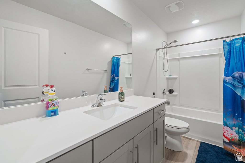 Bathroom featuring vanity, shower / bath combo with shower curtain, toilet, and wood finished floors