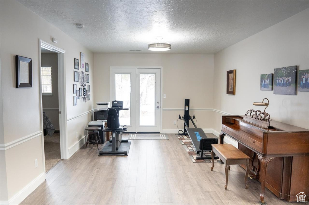 Workout room with light wood-style flooring, a textured ceiling, and baseboards