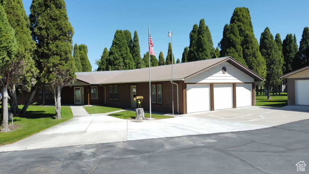 Ranch-style home featuring a front yard, a metal roof, and driveway