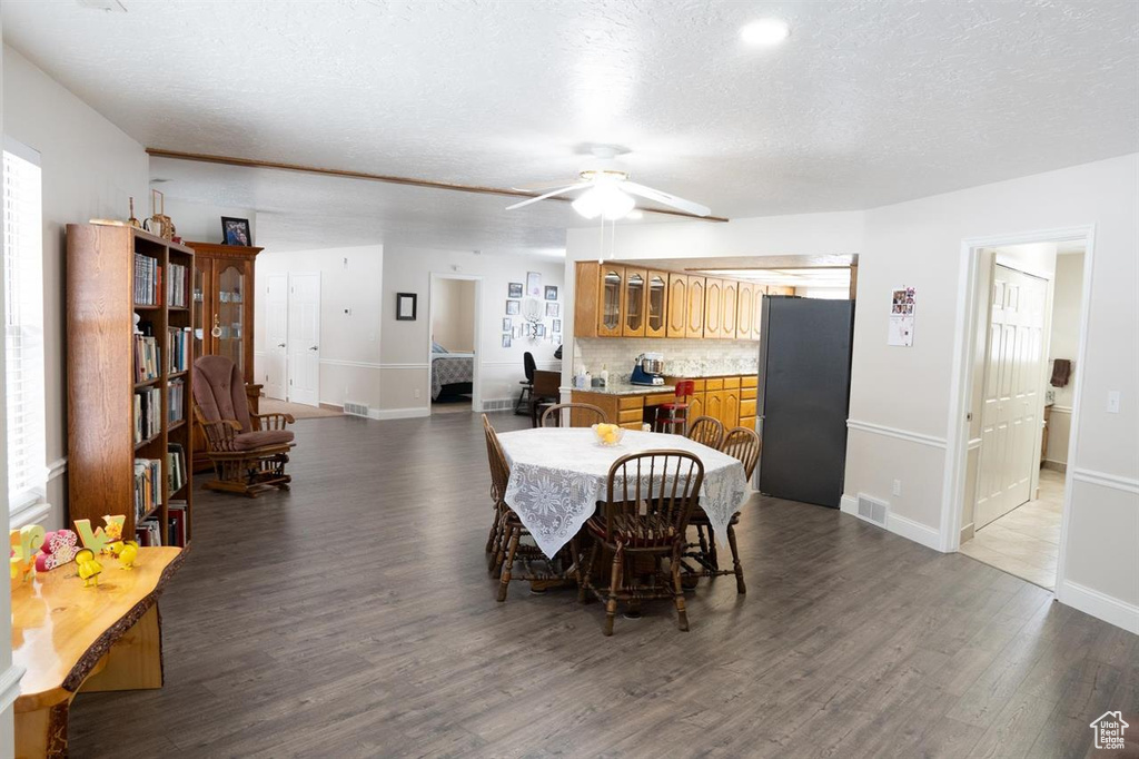 Dining room with wood finished floors, baseboards, a ceiling fan, and a textured ceiling