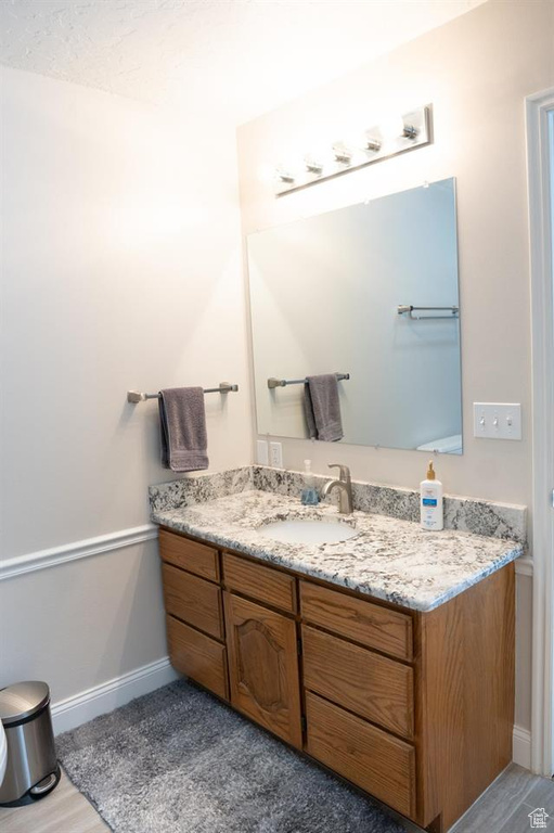 Bathroom featuring vanity, baseboards, and wood finished floors