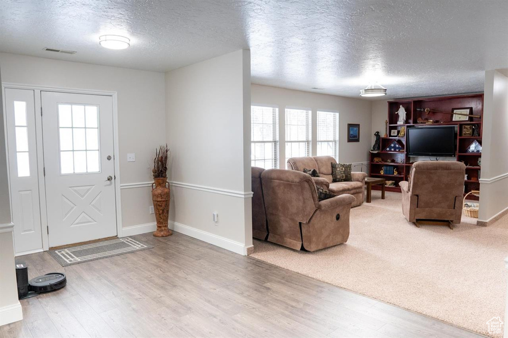 Foyer entrance featuring a textured ceiling, wood finished floors, and baseboards