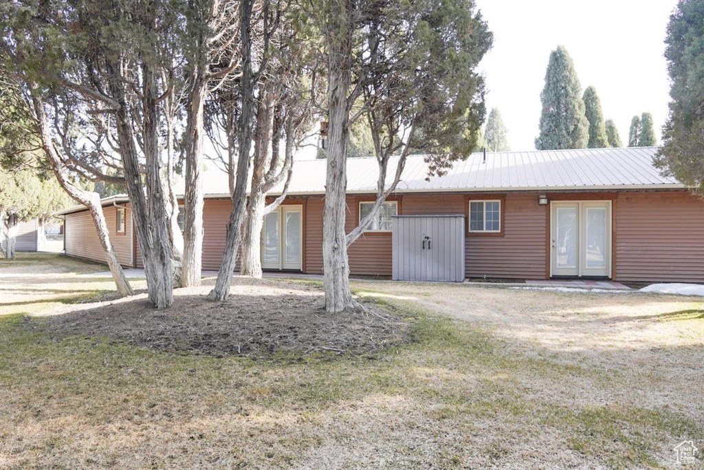 Single story home featuring french doors, metal roof, and a front yard