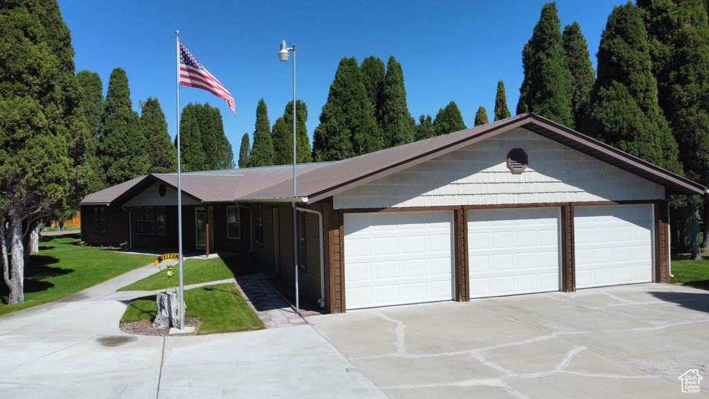Ranch-style home featuring driveway, a front lawn, and a garage