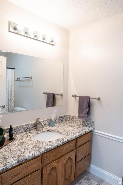 Full bath with toilet, vanity, and baseboards