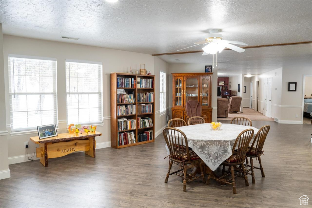 Dining room featuring a textured ceiling, wood finished floors, baseboards, and ceiling fan