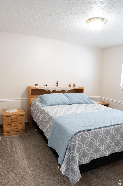 Carpeted bedroom featuring a textured ceiling and baseboards