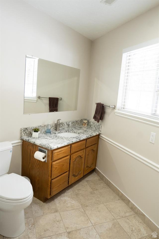 Bathroom with toilet, vanity, and baseboards