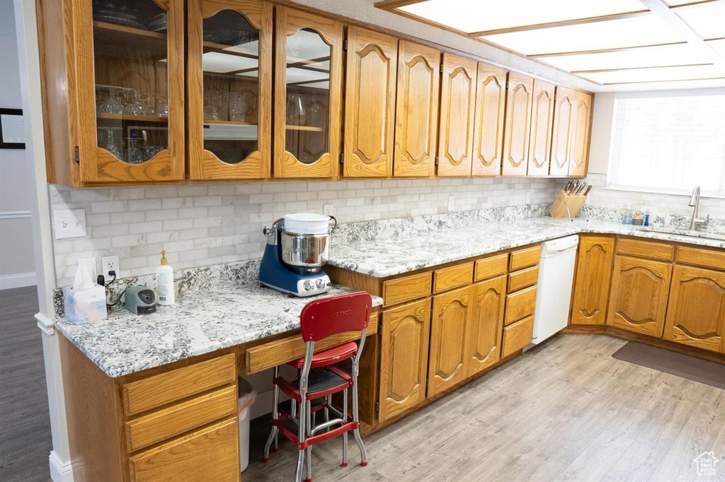 Kitchen featuring a sink, white dishwasher, decorative backsplash, and light wood-type flooring