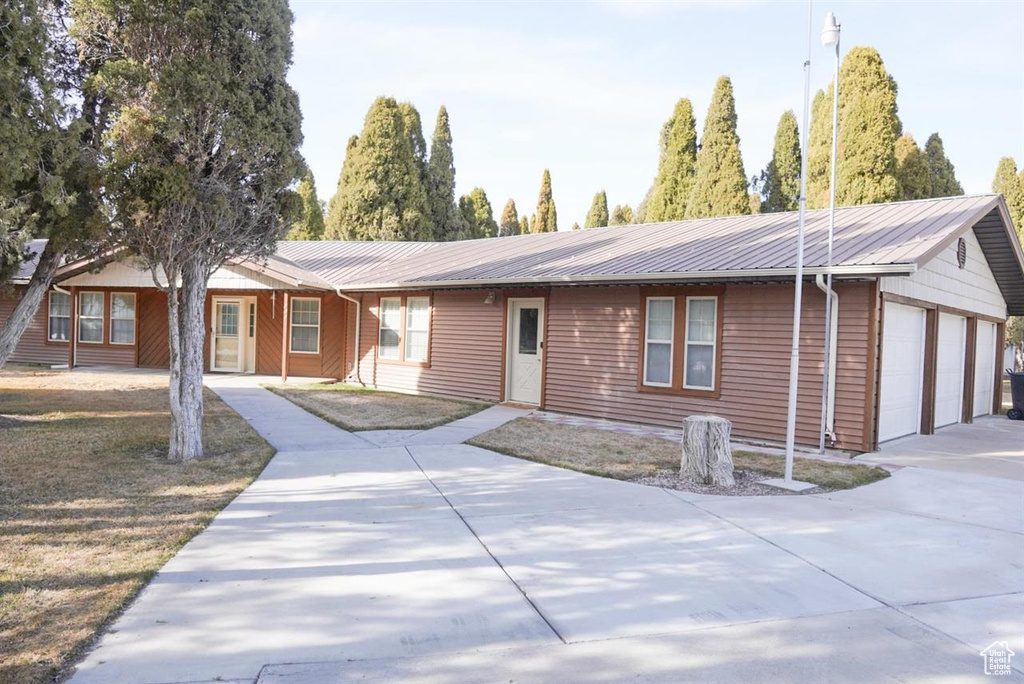 Ranch-style home featuring metal roof and driveway