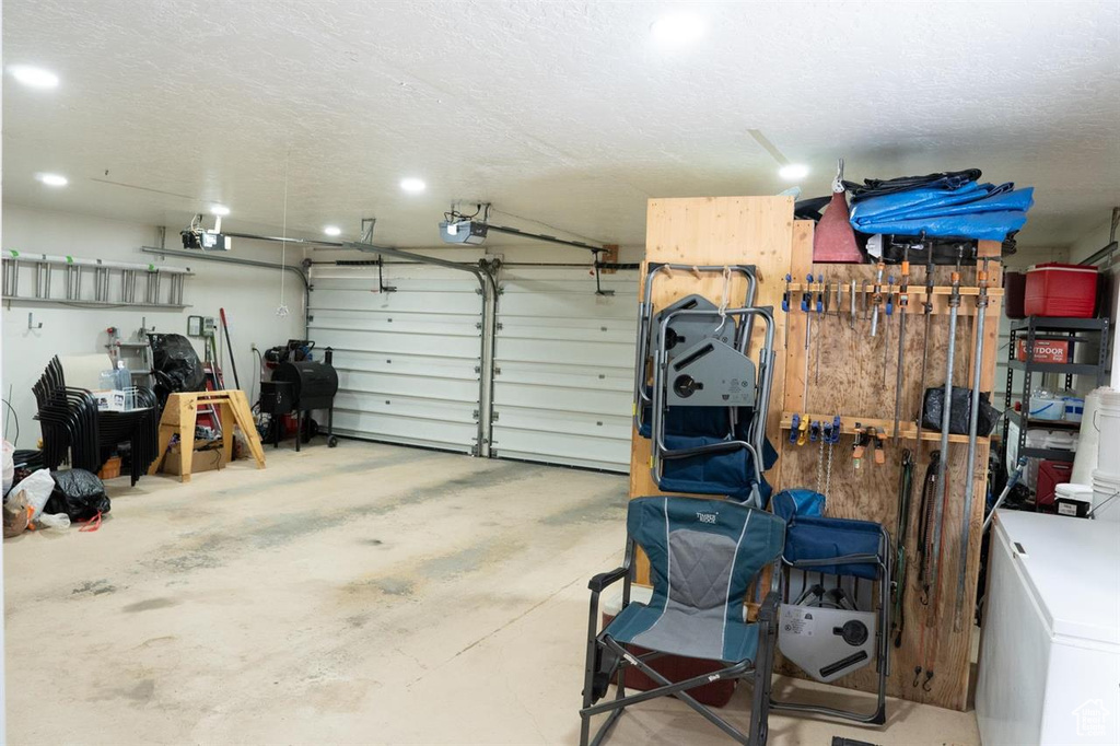 Garage with a garage door opener, recessed lighting, and refrigerator