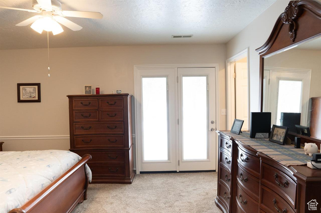 Bedroom with light colored carpet, access to outside, a textured ceiling, and ceiling fan