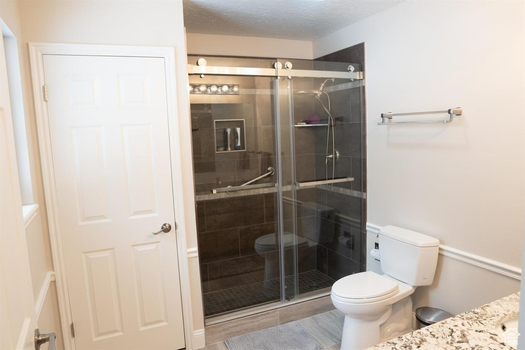 Bathroom featuring toilet, vanity, and a shower stall