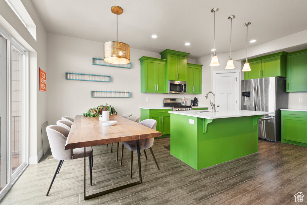Kitchen featuring green cabinets, stainless steel appliances, dark wood-style flooring, light countertops, and recessed lighting