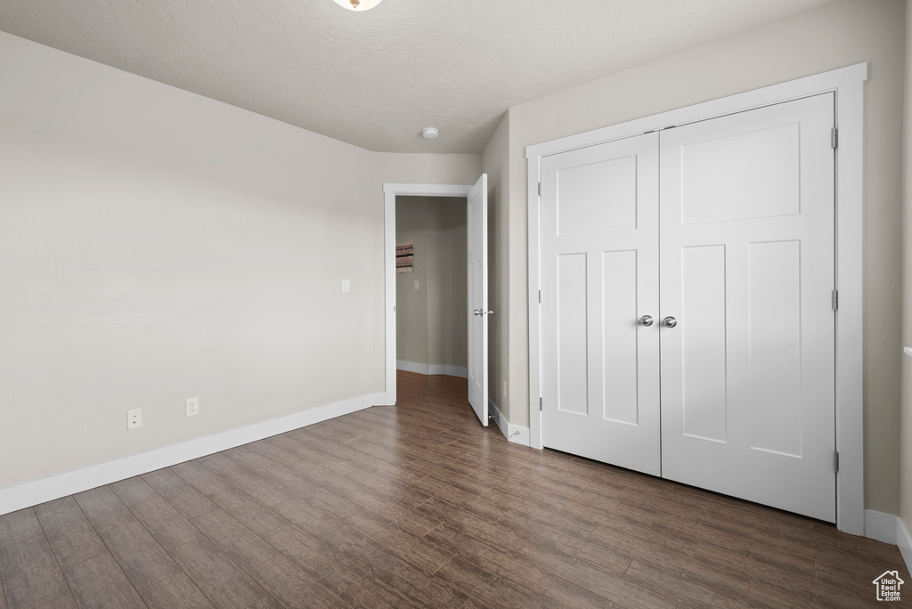 Unfurnished bedroom featuring wood finished floors, baseboards, and a closet